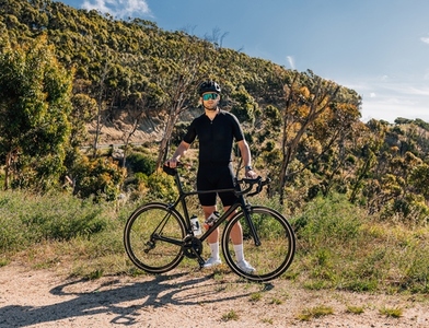 Sportsman in black fitness attire relaxing in wild terrain after a bicycle ride