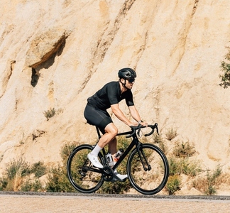 Professional triathlete in black sportswear riding road bike