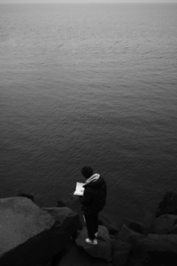 a boy writes looking at the sea