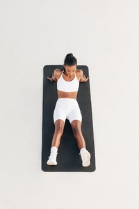Shot from above of a young sportswoman relaxing on a mat  Female in white fitness wear taking a break