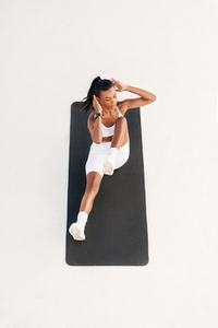 Young female doing core exercises on a mat outdoors  High angle of a woman doing abdominal exercises