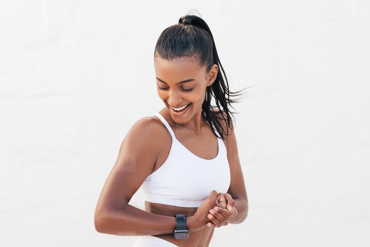 Happy female looking at her bicep. Young fit woman showing her muscles on the arm