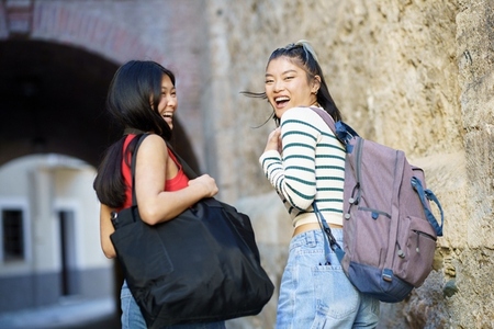 Cheerful Asian women with bags in street
