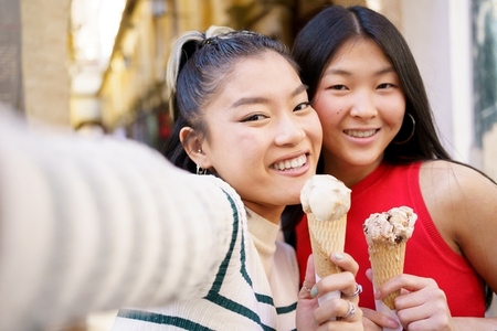 Happy Asian girlfriends taking selfie with ice creams