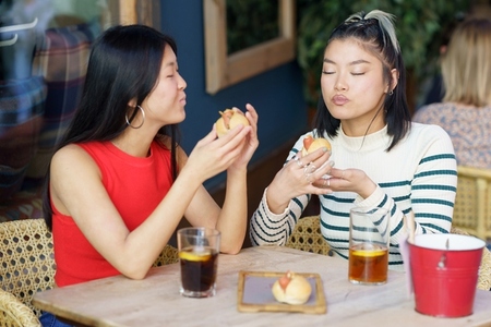 Satisfied Asian women eating tasty meal in cafe together
