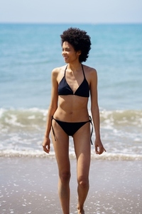 Positive black woman in swimwear near sea