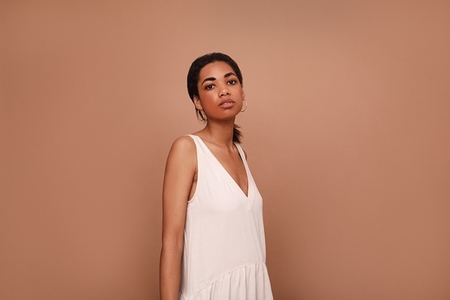 Young woman in a white dress against a brown background  Portrait of a female posing in the studio
