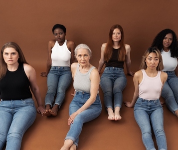 Six different females on a brown background  Group of six women with different body types and skin tones are looking at camera  Females of different ages in casuals sitting together in studio