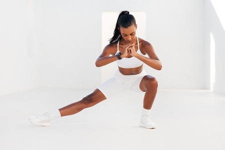 Strong female athlete in white fitness attire stretching body  Young woman warming up before exercises