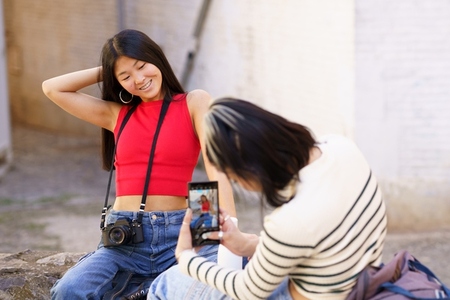 Female Asian tourists taking photo near brick building