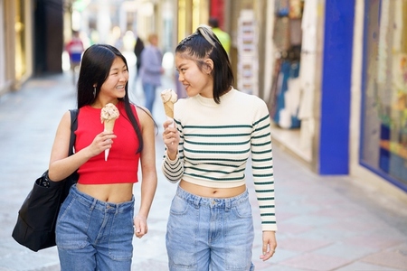Cheerful Asian women with ice cream in street