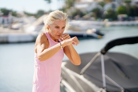Mature woman doing shadow boxing outdoors  Senior female doing sport in a coastal port