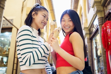 Smiling young Asian girlfriends with ice creams