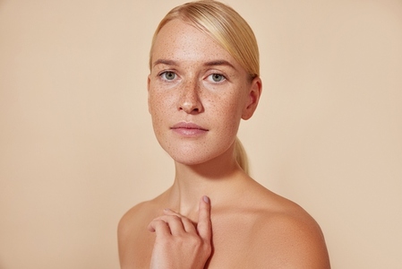 Portrait of a young blond female with freckles against pastel backdrop  Natural beauty woman with smooth skin