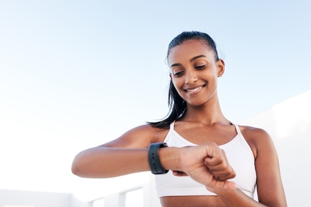 Portrait of a slim young woman checking her pulse on a smartwatch