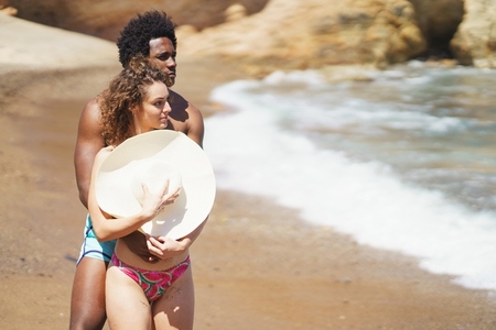 Multiracial couple hugging on beach