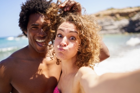 Selfie of funny diverse couple on seashore