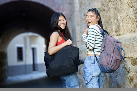 Cheerful Asian females with bags in street