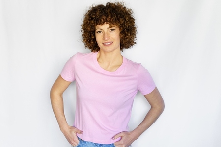 Calm woman with curly hair standing with hands clasped