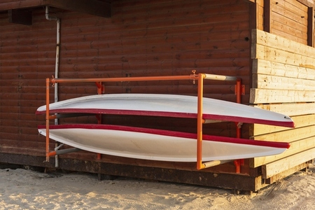 Red and white canoes on rack at shed