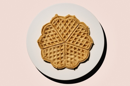 Still life scalloped heart shape waffles on plate on pink background