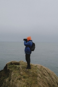 Photographer using camera on cliff above ocean Keiss