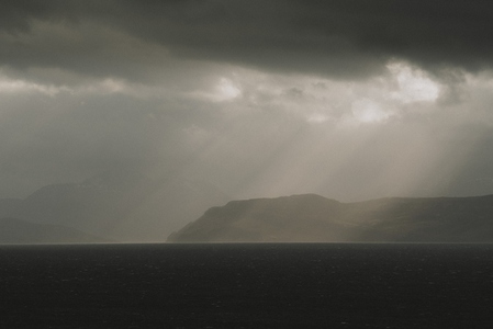 Rays of sunlight through clouds over cliffs and sea
