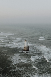 Aerial view waves around lighthouse on sea