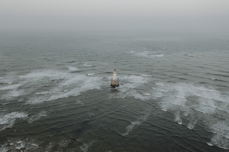 Aerial view waves around lighthouse in ocean