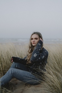 Portrait beautiful young woman sitting in beach grass