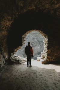 Man with backpack standing in abandoned castle archway