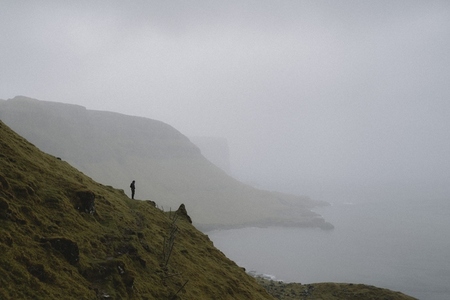 Man standing on foggy hillside above ocean