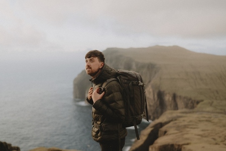 Man with backpack hiking on cliffs above ocean
