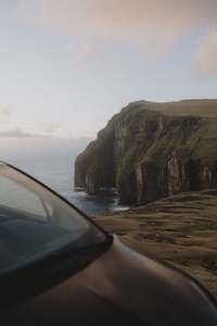 Majestic cliffs over ocean behind car