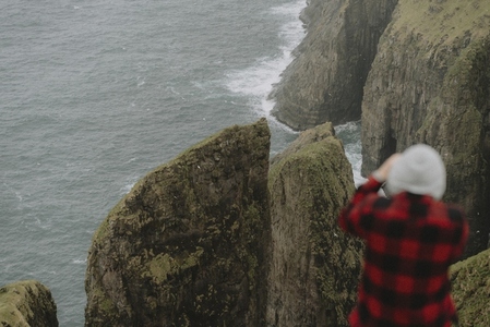 Man on cliff photographing sea stacks