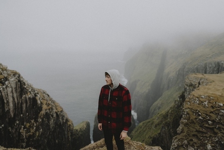 Hiker in fog on cliffs above sea stacks