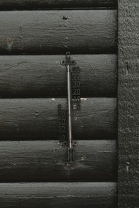 Cast iron thermometer on black wall of house