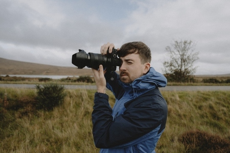 Male photographer using SLR camera in grassy field
