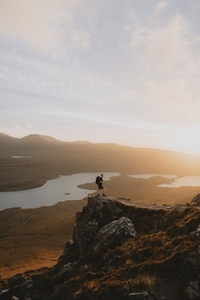 Hiker on rugged mountain overlooking scenic view at sunset