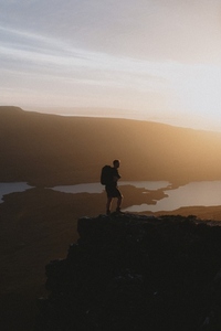 Silhouetted hiker on mountain at sunset
