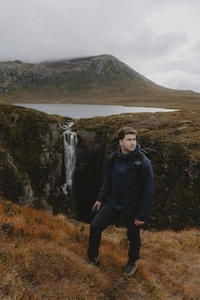 Man hiking along remote mountain waterfall