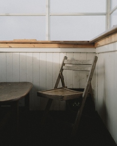 Sunlight over wooden folding chair at table below window