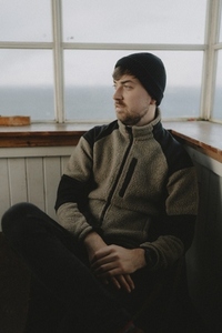 Thoughtful male hiker in beanie sitting at window