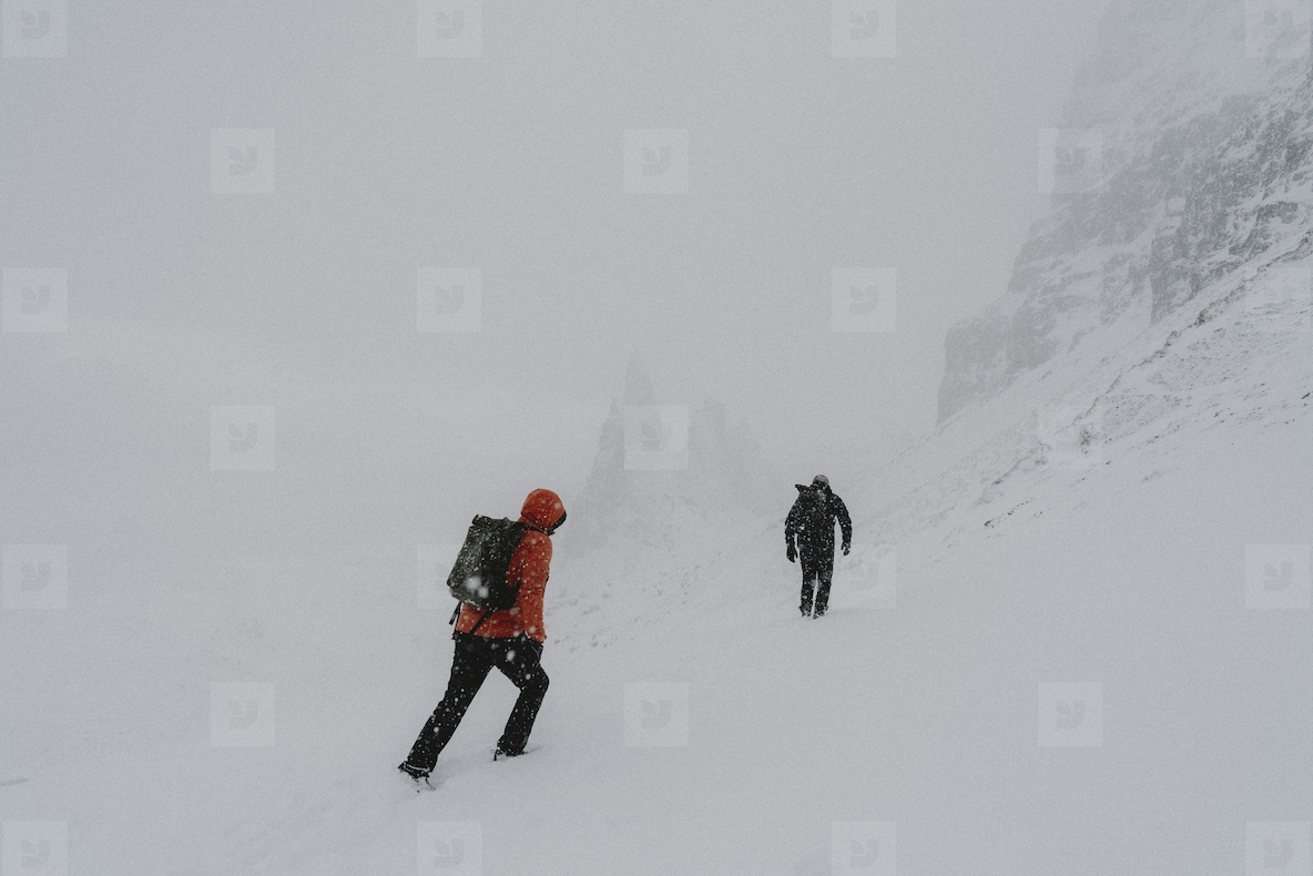 Hikers hiking up snow covered mountain slope