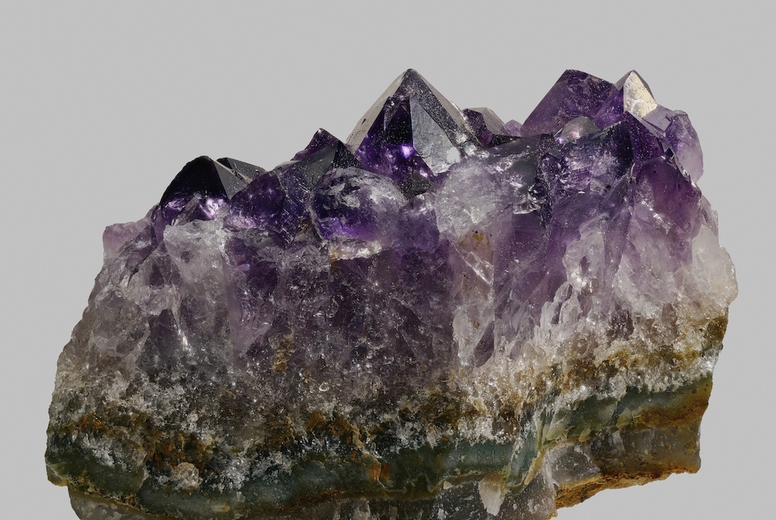 Close up textured purple Uruguayan amethyst crystal on gray background
