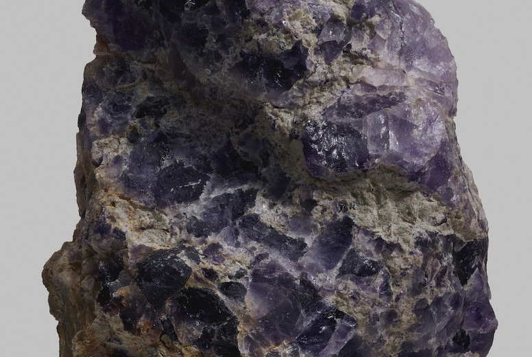 Close up detail textured purple Spanish fluorite stone on gray background