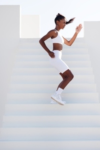 Full length of a slim female stepping down stairs outdoors  Young slim sports woman jogging on stairs