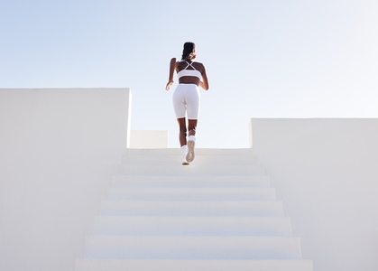 Rear view of a full length of a slim female athlete running up on stairs  Back view of a woman sprinting on stairs