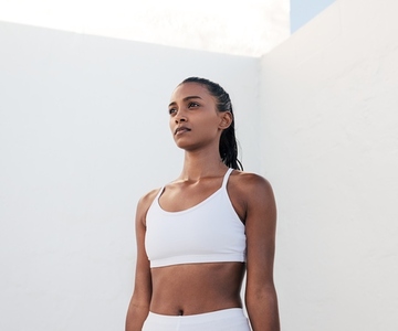 Slim confident sportswoman relaxing during exercises  Portrait of a fit female in white fitness attire