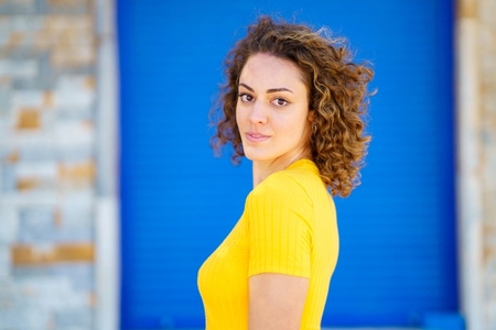 Content woman with curly hair against blurred street background